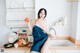 A woman sitting on a kitchen counter holding an apple.