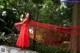 A woman in a red dress standing on a rock.