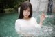 A woman in a white shirt is standing in the water.